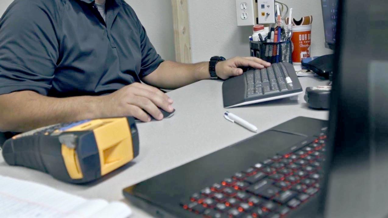 Employee working on a computer at a desk with tools nearby